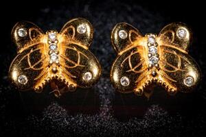 Elegant butterfly-shaped gold earrings with diamonds on a dark background. photo