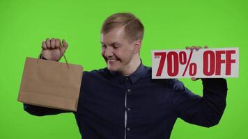 contento uomo mostrando shopping borse e su per 70 per cento via iscrizioni segni. bene vacanza sconti video