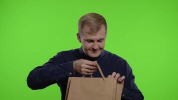 Man taking out sale discounts inscription from shopping bags, smiling satisfied with low prices video