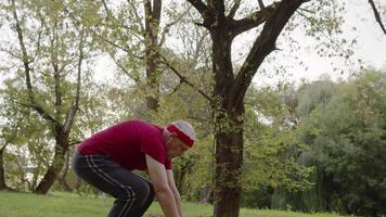 attivo anziano vecchio uomo fare sollevamento fisico esercizi nel parco. nonno formazione fitness allenarsi video