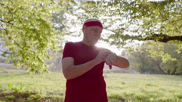 senior oud Mens rennen in park en gebruik makend van slim horloge, bijhouden resultaat na geschiktheid training video