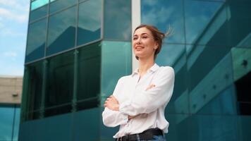 Smiling businesswoman standing arms crossed enjoying wind outside office video