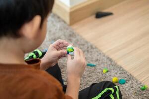 Asian boy playing with plasticine in the room photo