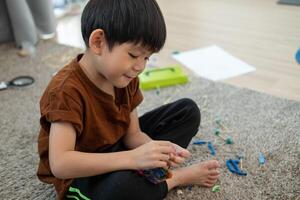 asiático chico jugando con arcilla de moldear en el habitación foto