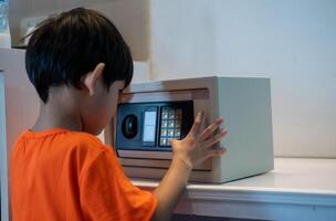 Little Asian boy opening safe at home photo