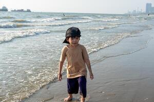 pequeño asiático chico jugando en el arena a el mar playa foto