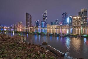 Ho Chi Minh City skyline and the Saigon River. Amazing colorful night view of skyscraper and other modern buildings at downtown. Travel concept photo