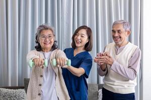 Senior couple get medical service visit from caregiver nurse at home while dumbbell exercising muscle strength in pension retirement center for rehabilitation and longevity post recovery process photo
