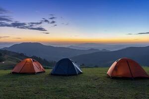 Group of adventurer tents during overnight camping site at the beautiful scenic sunset view point over layer of mountain for outdoor adventure vacation travel concept photo