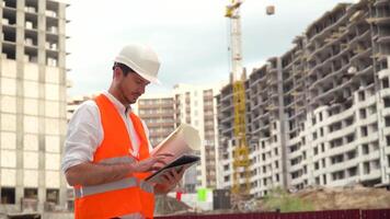 arquitecto o ingeniero laboral, hojeada edificio proyecto de construcción sitio con tableta. edificio construcción concepto video