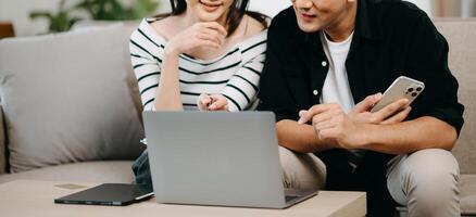 Female discussing new project with male colleague. Young woman talking with young Asian man with financial on sofa photo