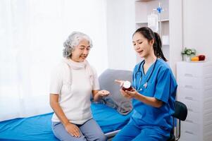 médico y asiático mayor paciente quien mentira en el cama mientras comprobación legumbres, consultar y explique con enfermero tomando Nota en hospital salas. foto