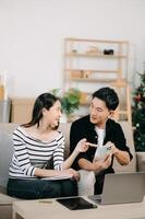 Female discussing new project with male colleague. Young woman talking with young Asian man with financial on sofa photo