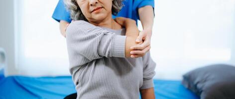 asiático fisioterapeuta Ayudar hembra paciente extensión brazo durante ejercicio correcto con pesa en mano durante formación mano foto
