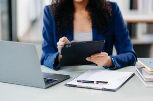 Confident businesswoman working on laptop,tablet and smartphone at her workplace photo