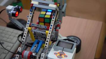 arte para robótica clase. un robot hecho desde un Lego conjunto y motor resuelve un de rubik cubo. desarrollo de sencillo juguete modelos y programas a escuela. Ucrania, Kiev - diciembre dieciséis, 2023. video