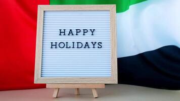 Text HAPPY HOLIDAYS on background waving flag of UAE. Independence Commemoration Day Muslim, Ramadan, Day of flag National holiday of United Arab Emirates. Arabian holidays. Dubai celebration video