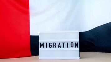 Lightbox with text MIGRATION on background of waving UAE flag made from silk. United Arab Emirates flag with concept of tourism and traveling. Inviting greeting card, advertisement. Dubai welcoming card video