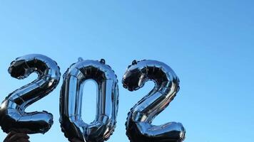 Silber vereiteln Nummer 2023 Veränderung zu 2024 Feier Neu Jahr Ballon auf Blau Himmel Hintergrund. glücklich Neu Jahr Schöne Grüße Konzept. Hände halten Luftballons zwei tausend dreiundzwanzigster Veränderung zu zwei tausend vierundzwanzig Jahr Weihnachten Urlaub 4k Aufnahmen video