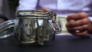 Man hands counting expenses banknotes of dollar cash from glass jar in the piggy bank and count them. Close up of hands unrecognizable Businessman. Save up budget investment concept. American bucks fund savings footage video