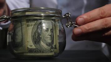 Man hands counting expenses banknotes of dollar cash from glass jar in the piggy bank and count them. Close up of hands unrecognizable Businessman. Save up budget investment concept. American bucks fund savings footage video