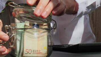 Man hands counting expenses banknotes of euro cash from glass jar in the piggy bank on calculator. Close up of hands unrecognizable Businessman. Save up budget investment concept. Euros fund savings footage video