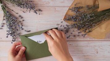 relaxar refrescar recarrega texto em solidário mensagem papel Nota lembrete a partir de verde envelope. plano deitar composição seco lavanda flores conceito do interior felicidade, desaceleração digital desintoxicação pessoal cumprimento. topo Visão video