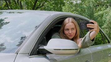 Blonde woman stoped car on road to take a selfie photo. Young tourist explore local travel making candid real moments. True emotions expressions of getting away and refresh relax on open clean air video