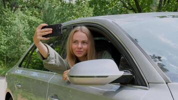 blond Frau gestoppt Auto auf Straße zu nehmen ein Selfie Foto. jung Tourist erkunden lokal Reise Herstellung offen echt Momente. wahr Emotionen Ausdrücke von bekommen Weg und Aktualisierung entspannen auf öffnen sauber Luft video