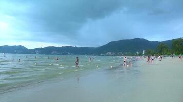 People playing on the sandy beach in the sea in summer. It's about to rain. Phuket in Thailand. video