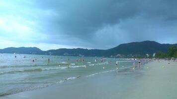 People playing on the sandy beach in the sea in summer. It's about to rain. Phuket in Thailand. video