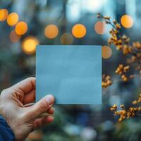 AI generated Hand holding blank blue paper with a soft bokeh background For Social Media Post Size photo