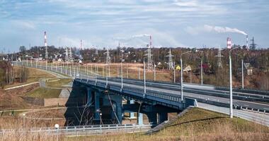 panorámico ver de un enorme la carretera puente dentro el de fumar chimeneas de un fábrica a través de un amplio río con activo tráfico video