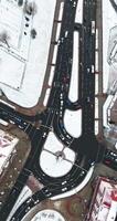 vertical accelerated video 4x aerial view above at crossroads on winter road junction with heavy traffic in city with snow