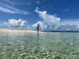 Man walking on the fine sand of a tropical beach on a sunny day. photo