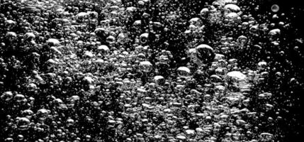 Soda water bubbles splashing underwater against black background. photo