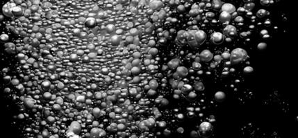 Soda water bubbles splashing underwater against black background. photo