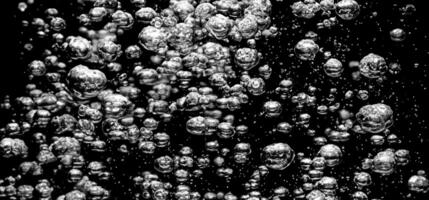 Soda water bubbles splashing underwater against black background. photo