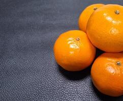 Image of fruit. Oranges stacked on black leather. photo