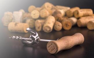 Wine corks and corkscrew on black wooden table in soft sunlight photo