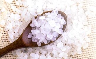 White bath salt in a wooden spoon on soft sunlight photo