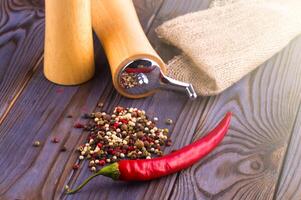 Black pepper corns, red hot chili pepper and Black pepper Powder on wooden background. photo