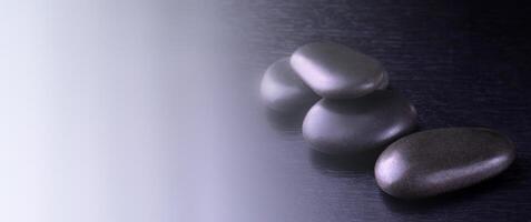 black stones for Thai spa on black wooden background on sunlight photo