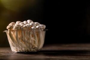 Closeup of a bunch of shimeji mushrooms on wooden board, with selective focus photo