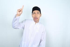 confused asian muslim man pointing above isolated on white background photo