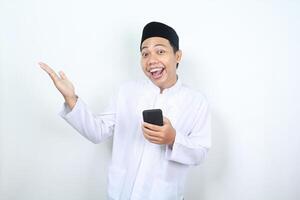 funny face of happy muslim asian man presenting hand to copy space with holding phone photo