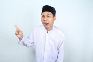 confused asian muslim man pointing to side isolated on white background photo