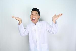 cheerful muslim asian man screaming while raising hand two side to presenting empty space isolated on white background photo