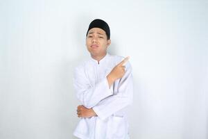 stressed muslim man asian pointing to empty side with folded hand isolated on white background photo