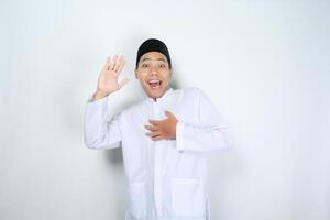 funny asian muslim man show surprised expression while waving hand say hello isolated on white background photo